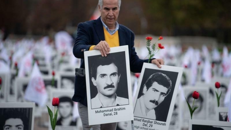 عضو في منظمة مجاهدي خلق الإيرانية المعارضة يعرض في فرنسا صورًا لضحايا سقطوا في إعدامات طالت آلاف السجناء السياسيين الإيرانيين في عام 1988