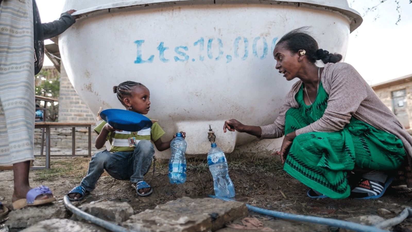 امرأة وطفلة من النازحين جراء الحرب تجمعان المياه في ميكيلي عاصمة تيغراي في شباط/ فبراير الماضي