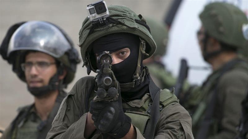 جندي إسرائيلي يصوب سلاحه باتجاه الفلسطينيين