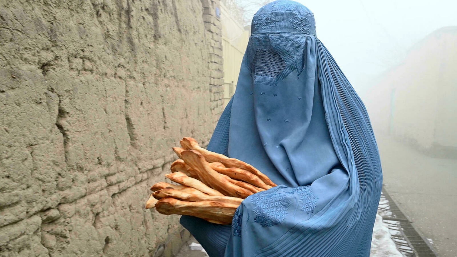 امرأة في أفغانستان تلقت خبزا تم توزيعه مجانيا في إطار حملة 