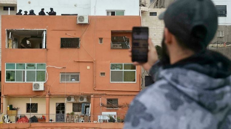 فلسطيني يلتقط صورا لقوات إسرائيلية تقف على سطح منزل عائلة الفلسطيني فادي أبو شخيدم منفذ هجوم بسلاح ناري في البلدة القديمة من القدس الشرقية المحتلة بعد أن قامت القوات الإسرائيلية بتدمير جدران المنزل وإغلاقه في الأول من فبراير 2022