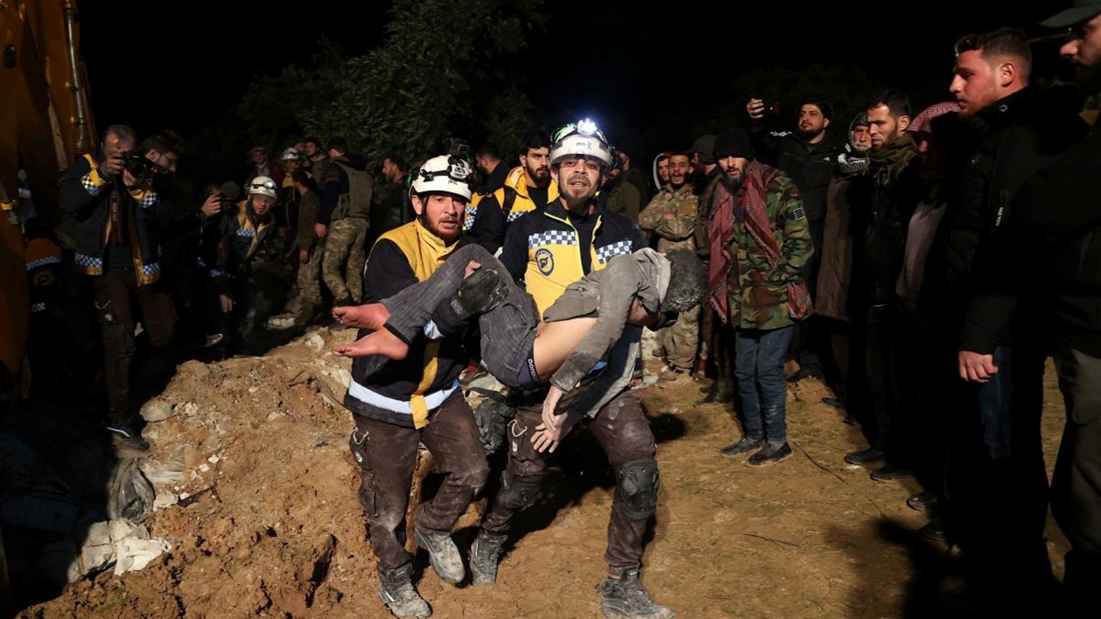 عمال إنقاذ يحملون جثة صبي قضى جراء القصف على سوريا