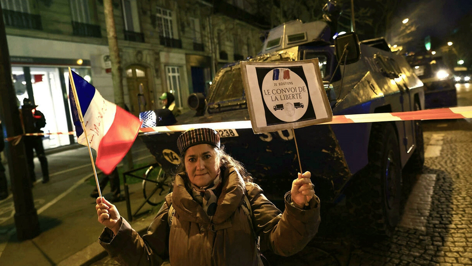 متظاهرة ترفع العلم الفرنسي أمام العربات المصفحة لقوات الدرك في شوارع باريس فيما تستعد الشرطة لمنع وصول قافلة الاحتجاج 