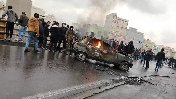 متظاهرون إيرانيون يتجمعون حول سيارة مشتعلة خلال تظاهرة في طهران، في 16 نوفمبر 2019.