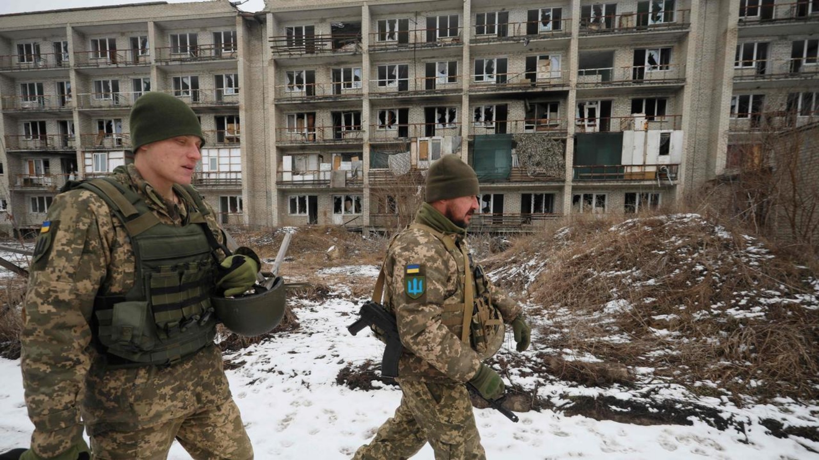 جنود من القوات العسكرية الأوكرانية يسيرون أمام المباني المتضررة على خط المواجهة مع الانفصاليين المدعومين من روسيا في ماريينكا بمنطقة دونيتسك في 7 فبراير 2022