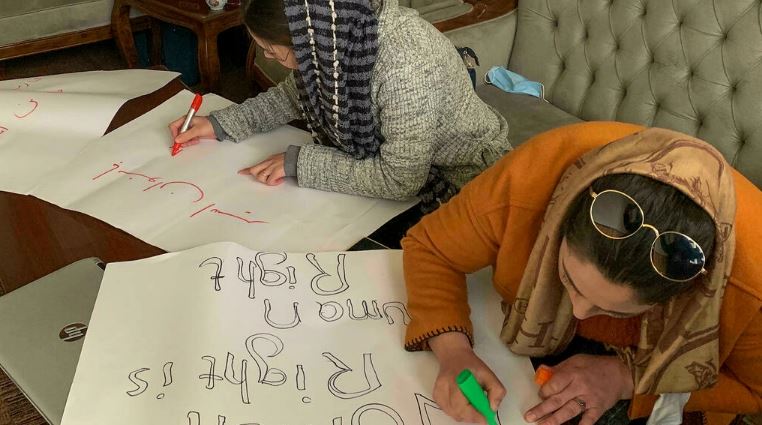 صورة ملتقطة في 15 يناير 2022 تظهر نساء أفغانيات يكتبن على لافتات استعدادا لمسيرة لحقوق المرأة في كابول