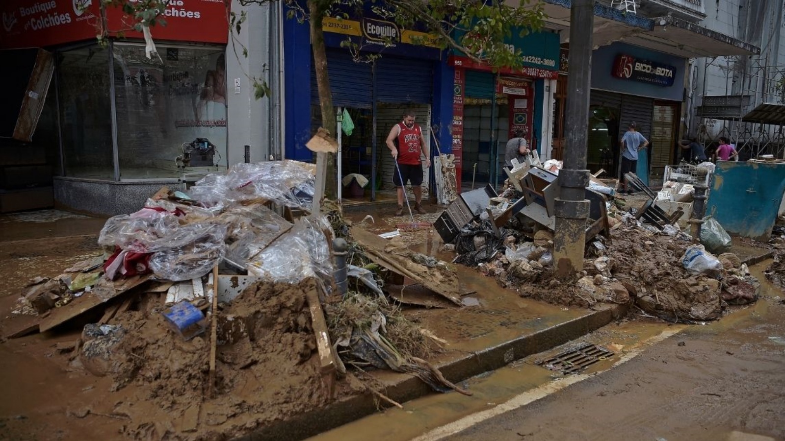 أصحاب المحال التجارية يعاينون الأضرار التي خلفتها الفيضانات، في مدينة بيتروبوليس البرازيلية