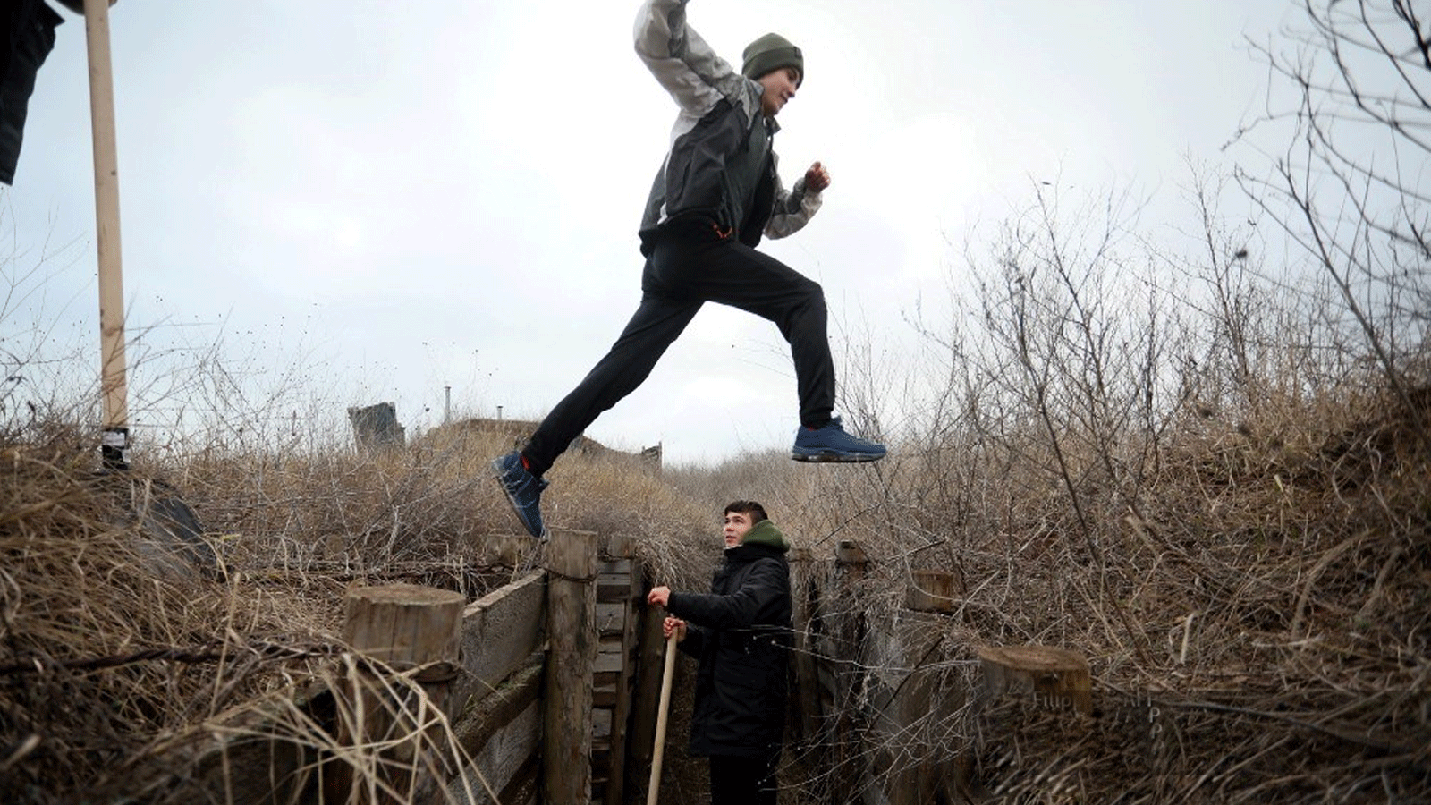 مراهقان أوكرانيان في محيط الخنادق المحفورة تحسباً لغزوٍ روسي