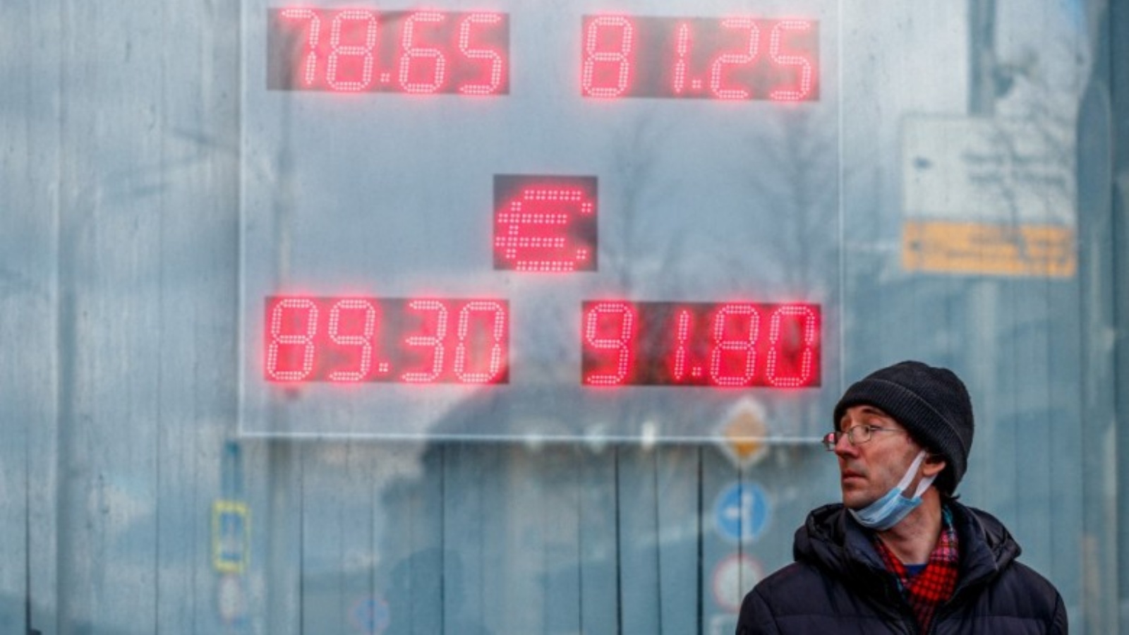 رجل أمام لافتة محل صيرفة يعرض سعر صرف الروبل الروسي مقابل الدولار