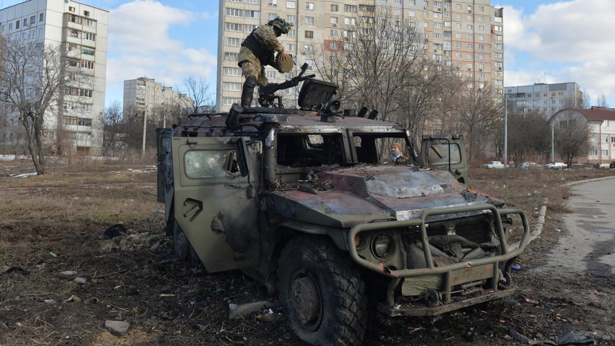 مقاتل أوكراني يفحص مركبة نقل مشاة روسية مدمرة بعد هجوم فاشل على خاركيف في 27 فبراير 2022