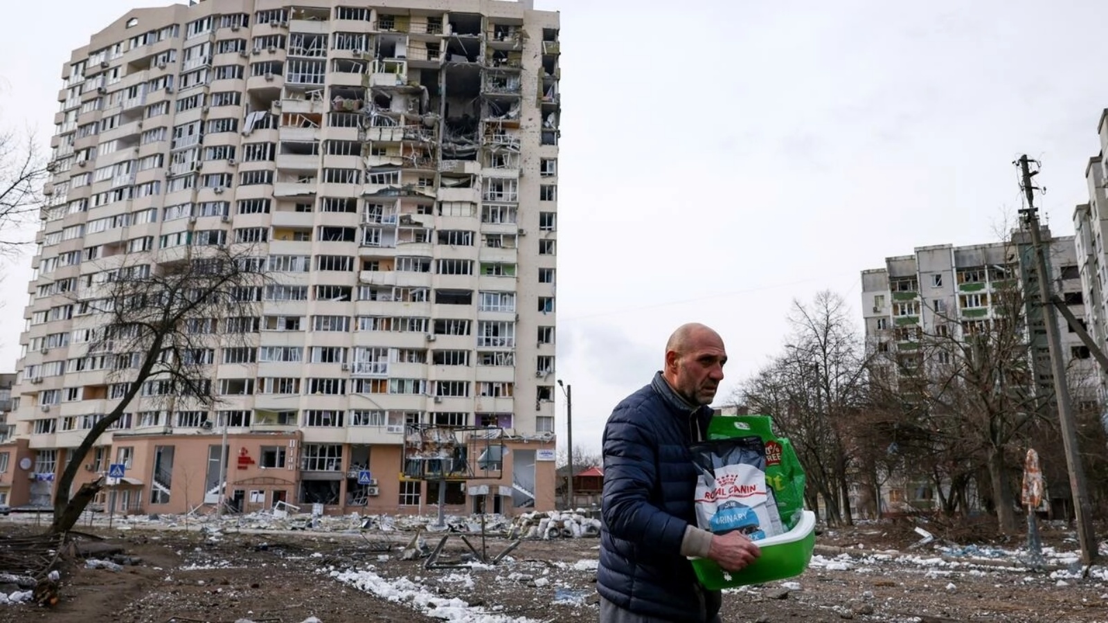 رجل يحمل أغراضاً أمام مبنى تضرر في القصف في تشيرنيهيف بأوكرانيا في الرابع من مارس 2022 