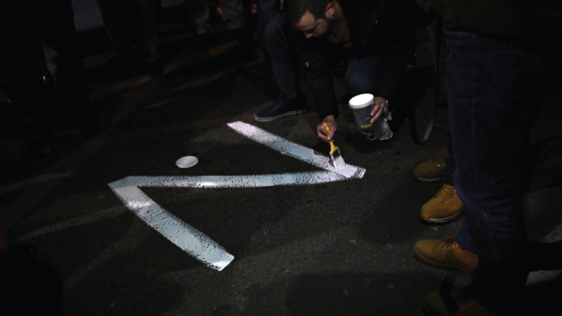 أحد المتظاهرين يرسم علامة "Z" في أحد الشوارع في إشارة إلى الدبابات الروسية التي تم تمييزها بالحرف ، خلال مسيرة نظمتها المنظمات اليمينية الصربية لدعم الغزو الروسي لأوكرانيا، في بلغراد، 4 مارس 2022