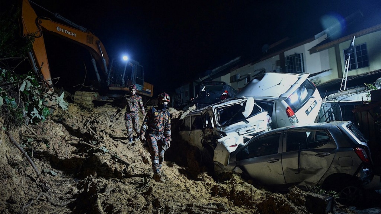 عمال الإنقاذ يبحثون عن الضحايا بعد حدوث انهيار أرضي بسبب هطول أمطار غزيرة في بلدة أمبانغ، خارج كوالالمبور في وقت مبكر من 11 مارس 2022