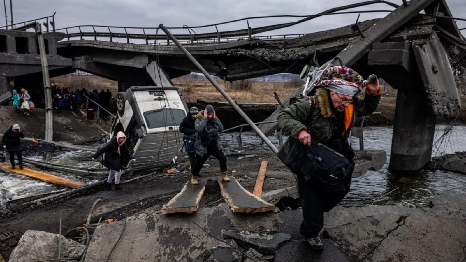 مدنيون تم إجلاؤهم يعبرون جسرًا مدمرًا أثناء فرارهم من القصف الروسي. في 7 مارس