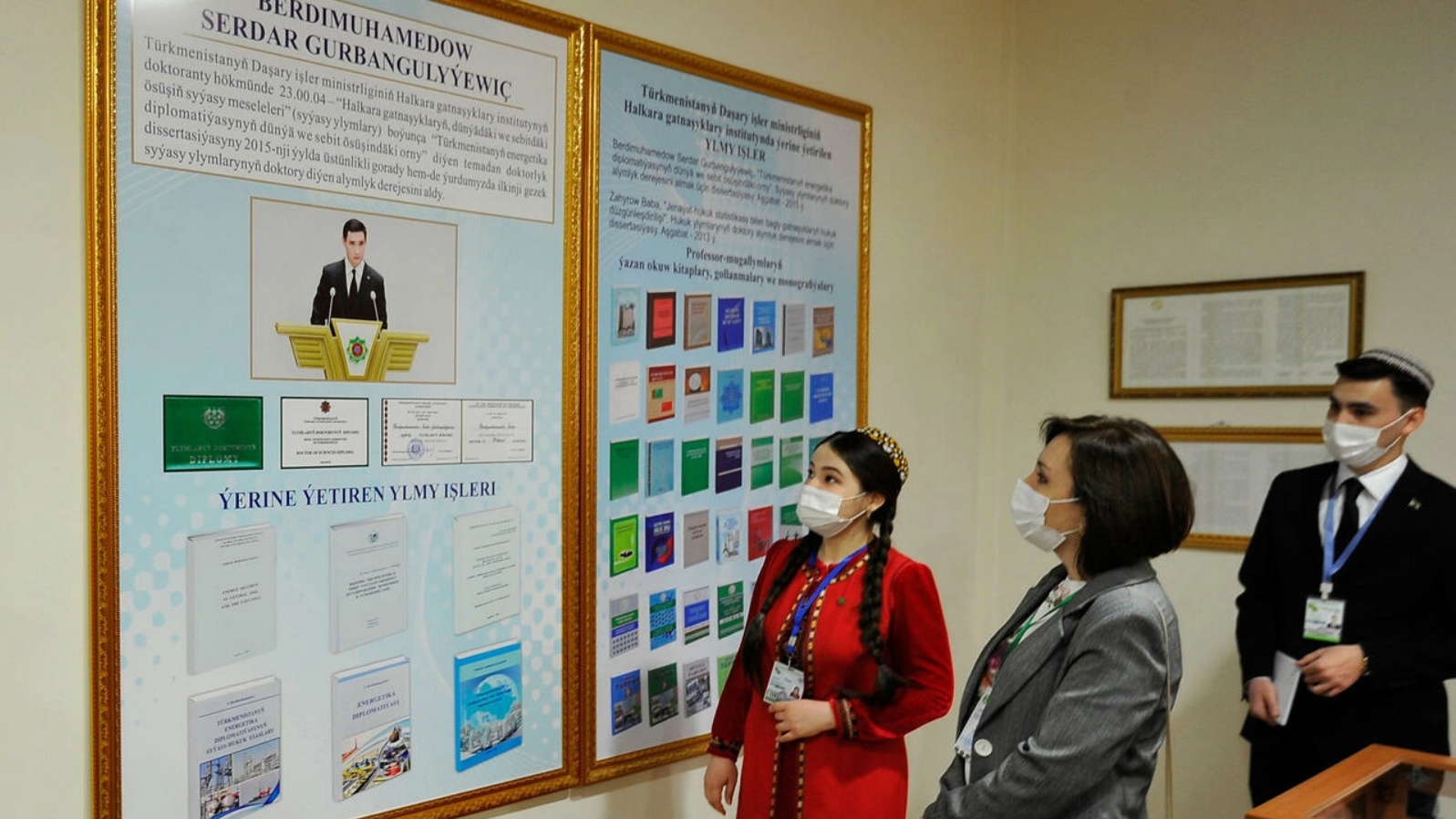 أفراد ينظرون إلى لوحة إعلانية تصور سيردار بردي محمدوف، نجل الرئيس المنتهية ولايته قربان قولي بردي موخمدوف في مركز اقتراع خلال الانتخابات الرئاسية في عشق أباد في 12 مارس 2022