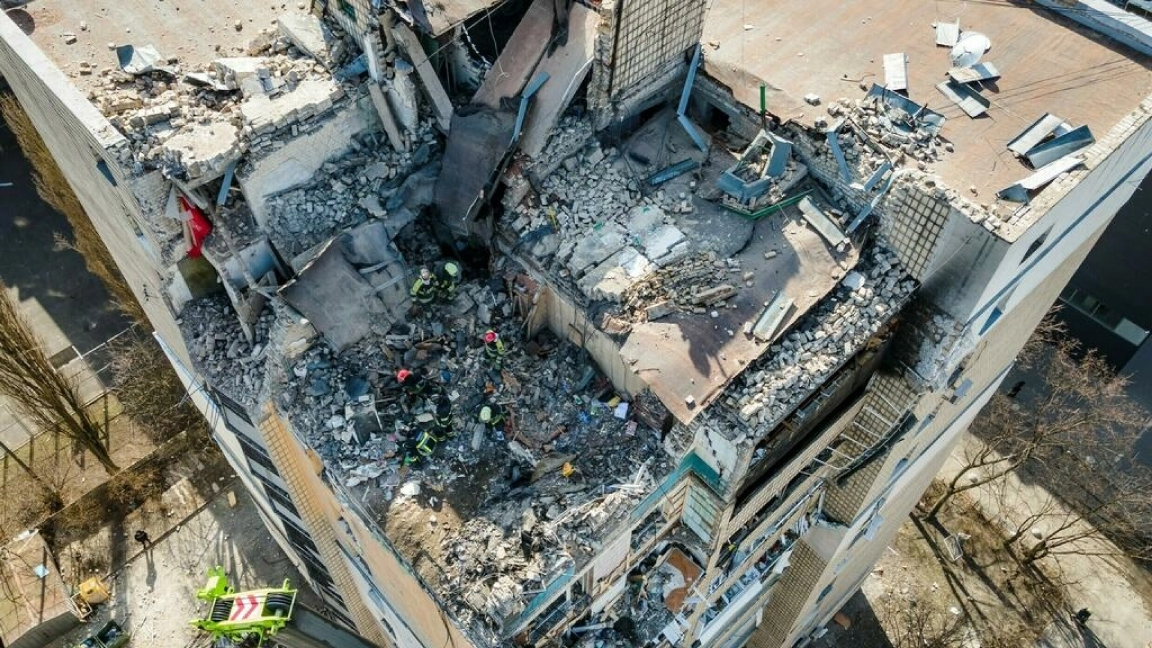 صورة جوية تظهر رجال الإطفاء وهم يعملون وسط أنقاض مبنى سكني أصابته حطام صاروخ سقط في كييف في 17 مارس 2022.