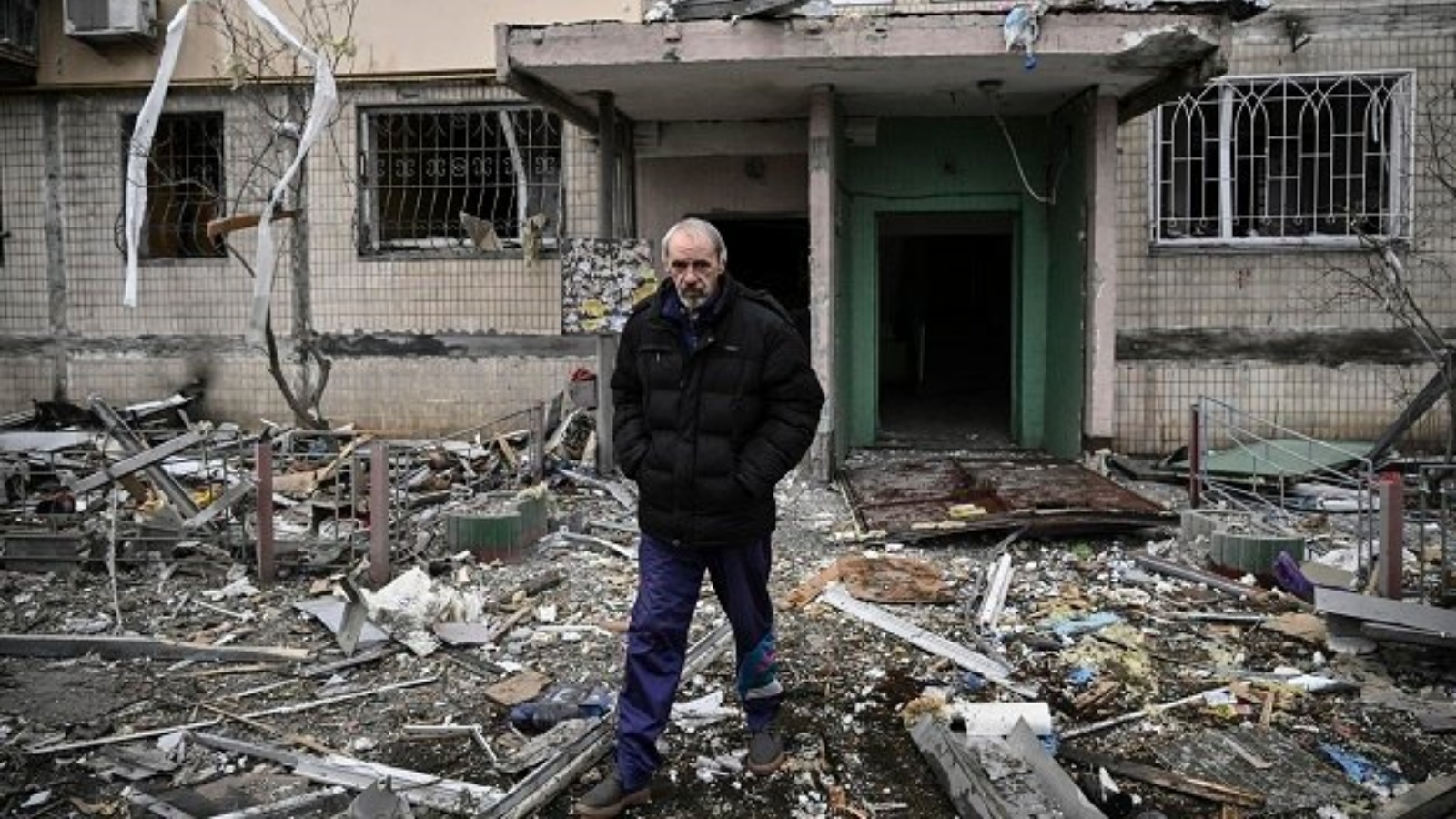 رجل عند مدخل مبنى سكني مدمر في أعقاب قصف حي أوبولون شمال غرب كييف.