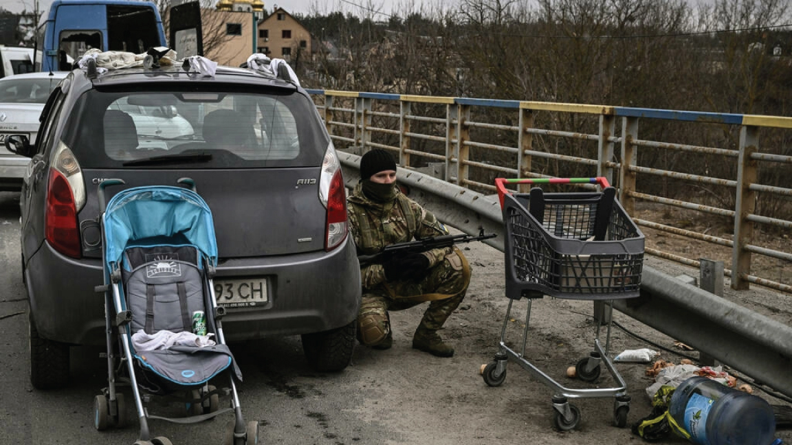 جندي أوكراني يختبئ خلف سيارة في إيربين يوم الأحد. شهدت ضاحية كييف بعض أعنف المعارك منذ غزو روسيا لأوكرانيا