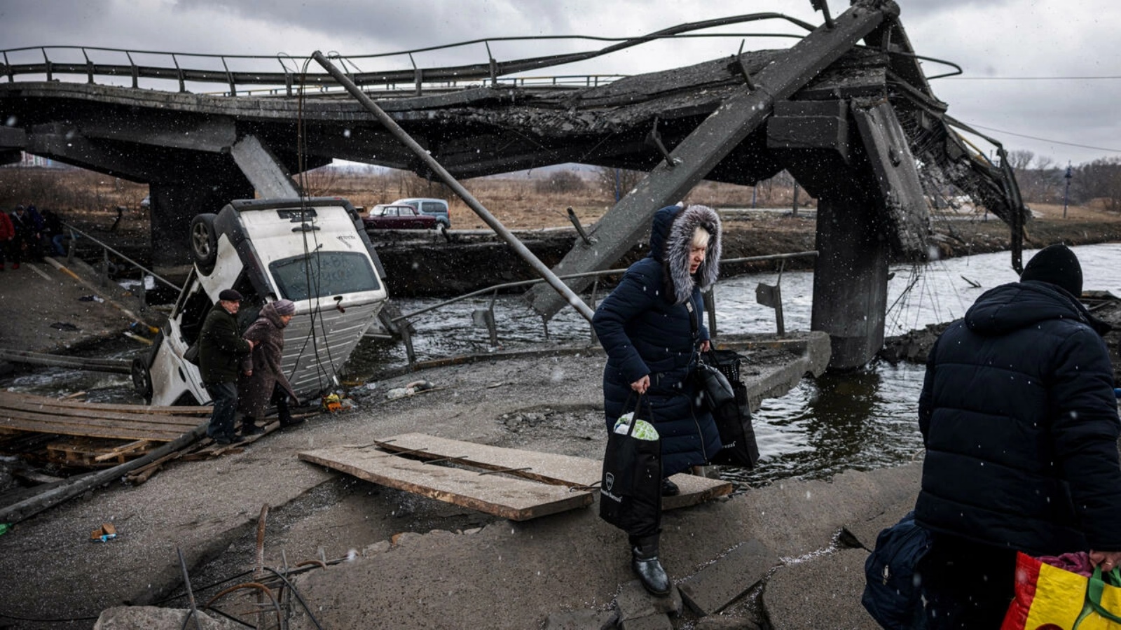 أوكرانيون يفرون من مدينة إربين في شمال غرب كييف ويعبرون نهرًا قرب جسر مدمّر في 13 مارس 2022