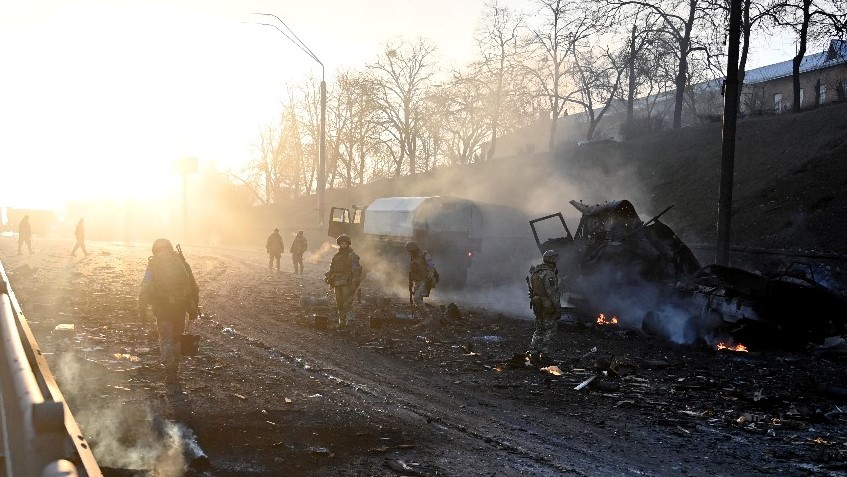 جنود أوكرانيون بجانب قافلة روسية مدمرة في إحدى ضواحي كييف