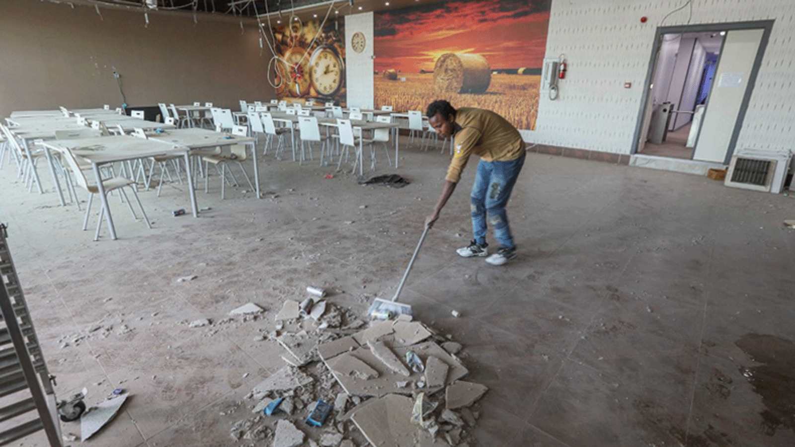  رجلٌ ينظف الأنقاض في الاستوديوهات المتضررة في مبنى تلفزيون كوردستان 24 بعد سقوط عشرات الصواريخ الباليستية في مكان قريب في إقليم كردستان أربيل، 13 مارس/ آذار 2022.
