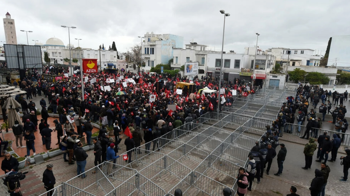 متظاهرون تونسيون يرفعون لافتات والأعلام الوطنية خلال احتجاج ضد الرئيس قيس سعيّد على مقربة من مبنى البرلمان في العاصمة تونس في 20 آذار/مارس 2022
