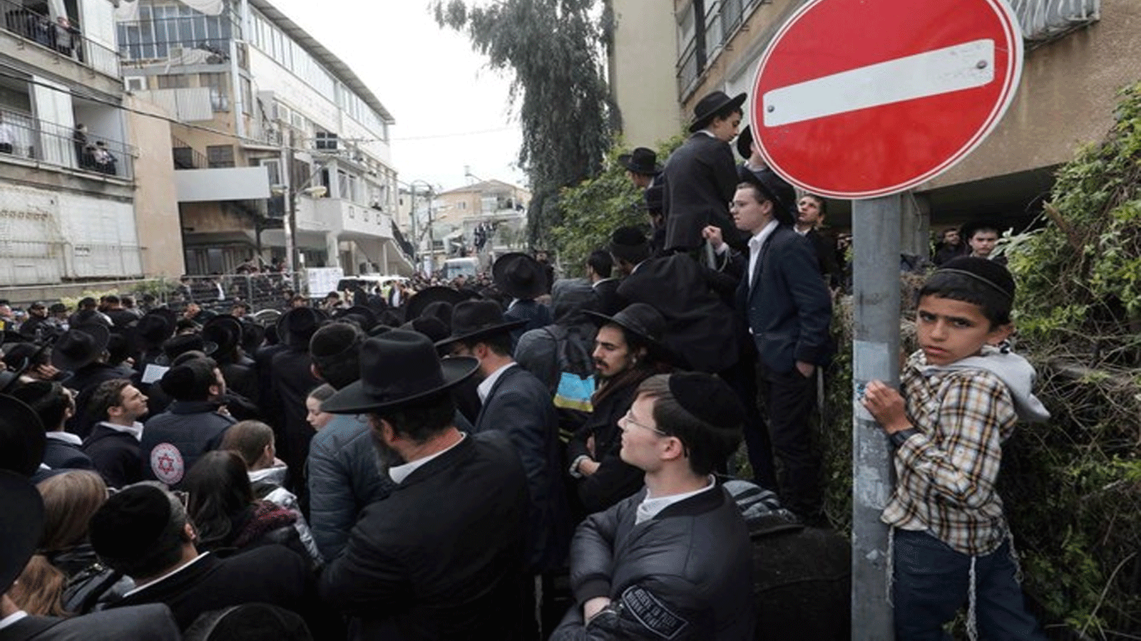 رجال وأطفال يهود متشددون يتجمعون خارج منزل الحاخام الراحل حاييم كانيفسكي، قبل جنازته في مدينة بني براك الإسرائيلية بالقرب من تل أبيب.20 آذار\مارس 2022.