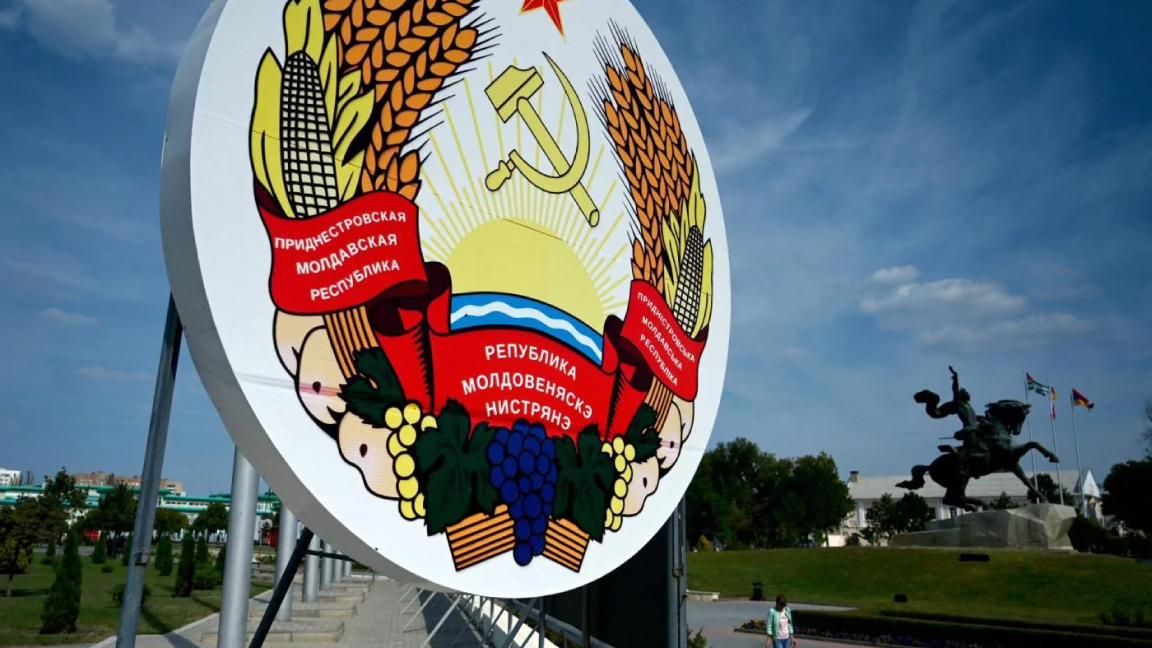امرأة تمشي أمام شعار نبالة ضخم من ترانسنيستريا في عاصمة المنطقة الانفصالية ، تيراسبول
