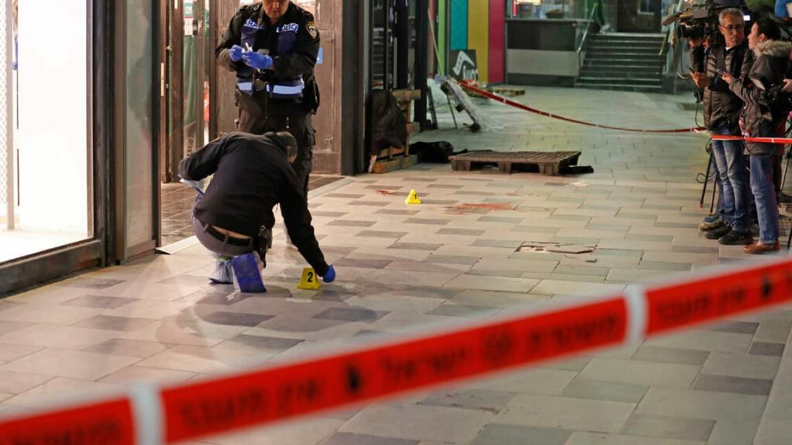 عناصر من الشرطة الإسرائيلية يجرون أعمال تمشيط لموقع الهجوم بسكين خارج مركز تجاري في مدينة بئر السبع (جنوب) اسفرت عن مقتل أربعة وجرح آخرين في 22 مارس 2022
