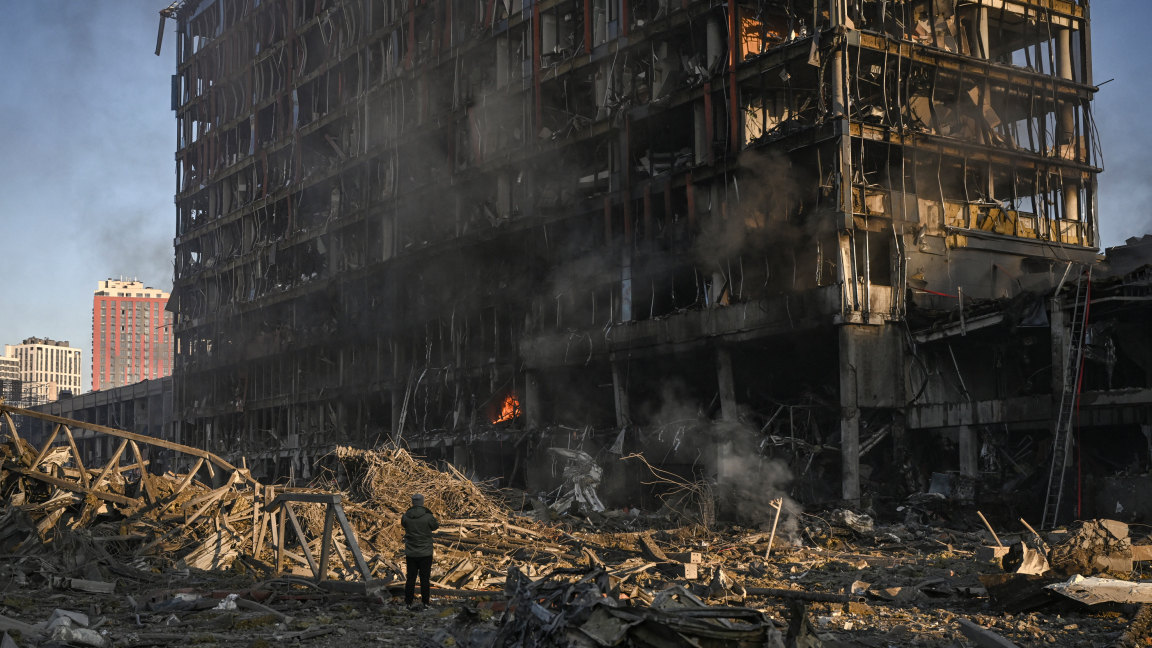 رجل يقف ينظر إلى مركز التسوق ريتروفيل المحترق والمدمّر