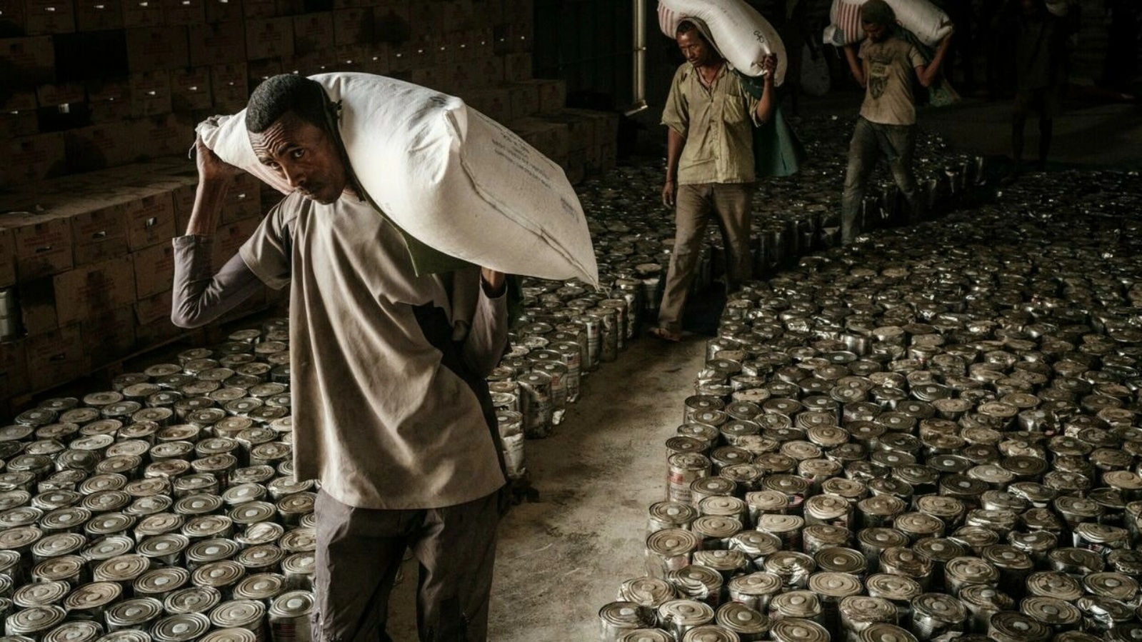 عمال يحملون أكياساً من الطحين لتوزيع مساعدات غذائية على نازحين فروا من العنف في إقليم تيغراي الإثيوبي في ميكيلي عاصمة الإقليم في 22 يونيو 2021