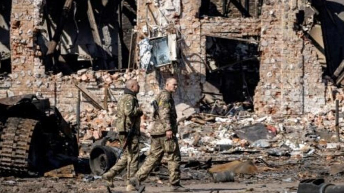 جنود أوكرانيون أمام مبان مدمرة في تروستيانتس في 29 مارس 2022