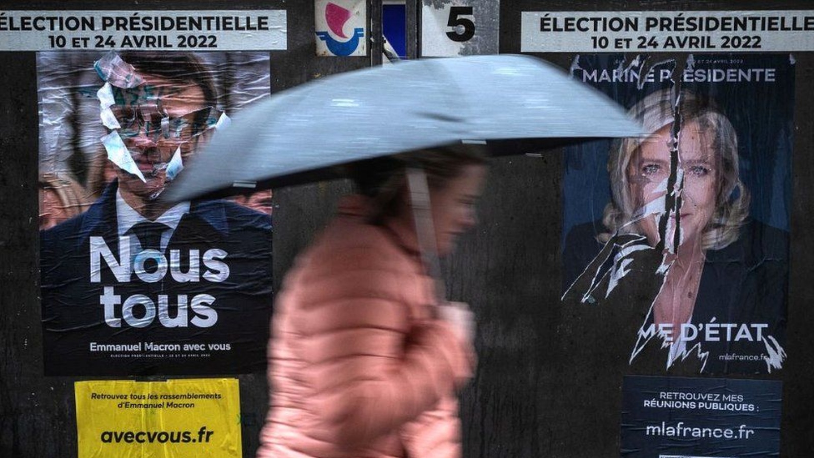 امرأة تمر أمام صورتين للمرشحين على الانتخابات الرئاسية الفرنسية ماكرون ولوبن
