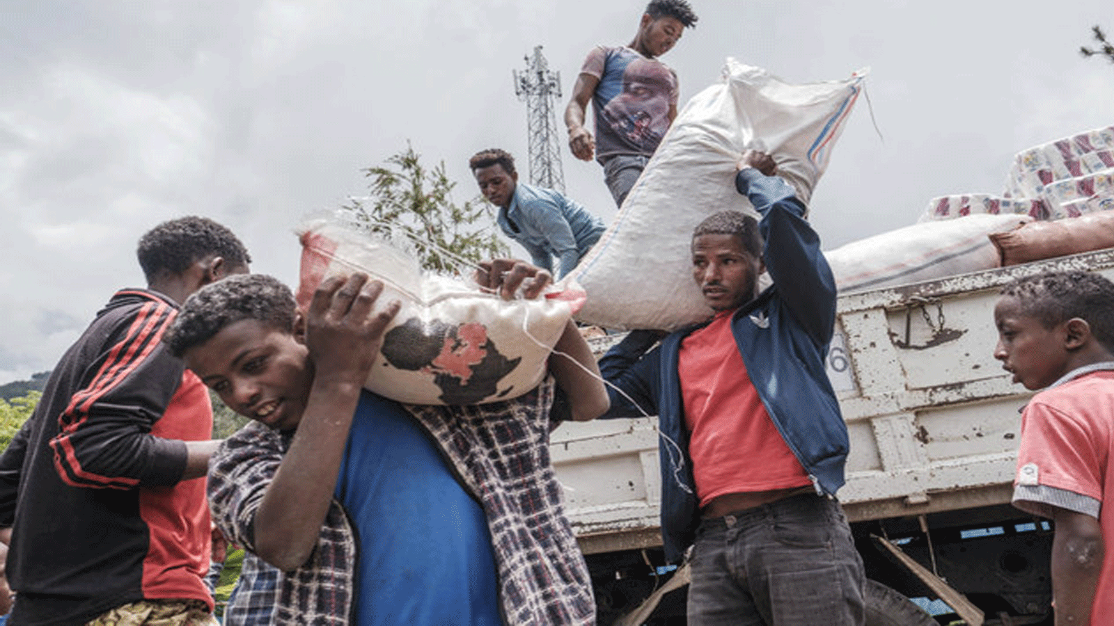 مدنيون نزحوا بسبب القتال في شمال إثيوبيا يفرغون الطعام والإمدادات من شاحنة في ملجأ مؤقت في مدينة ديسي.