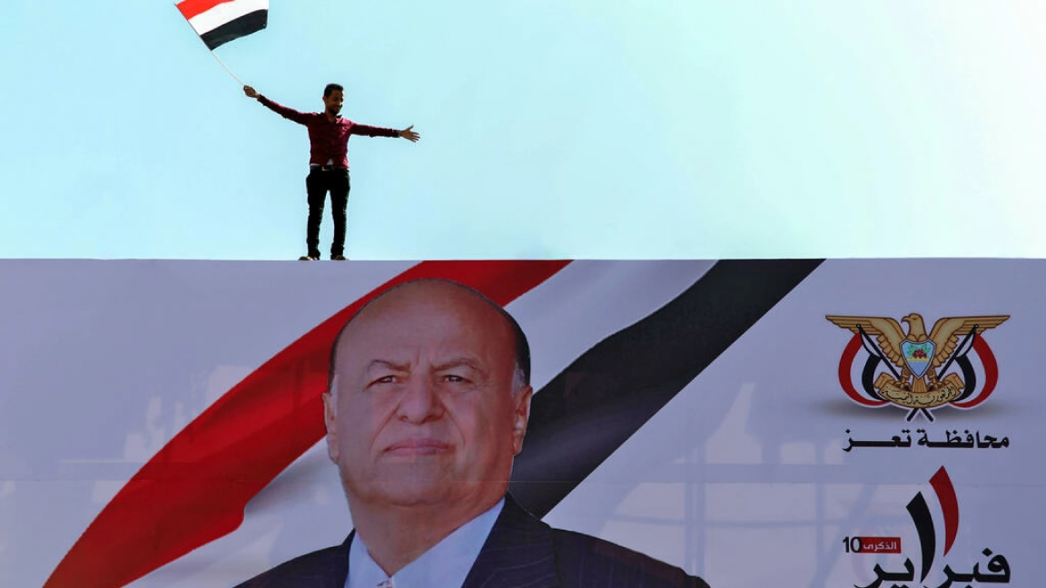 يمني يرفع العلم الوطني فوق صورة للرئيس عبد ربه منصور هادي في تعز بتاريخ 11 فبراير 2021