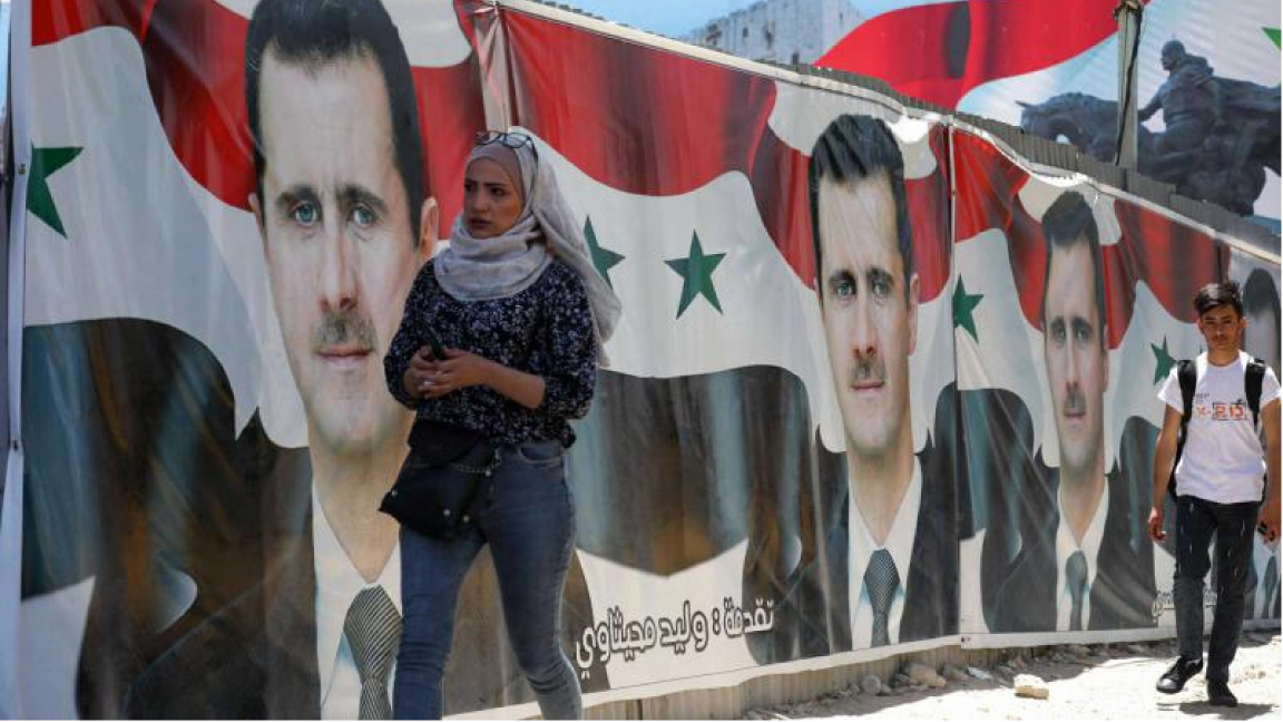 أشخاص يمرون من أمام لوحات إعلانية لحملة انتخابية تصور الرئيس السوري بشار الأسد، خلال حملة الانتخابات الرئاسية الماضية في دمشق