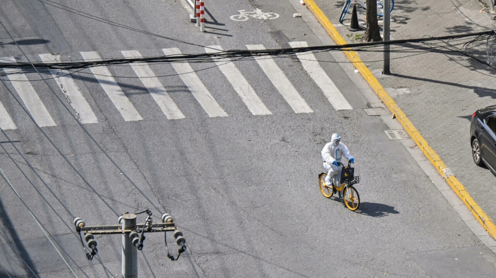 عامل صحة بملابس واقية يعبر شارعاً في شنغهاي على دراجة خلال تدابير إغلاق في 8 أبريل 2022