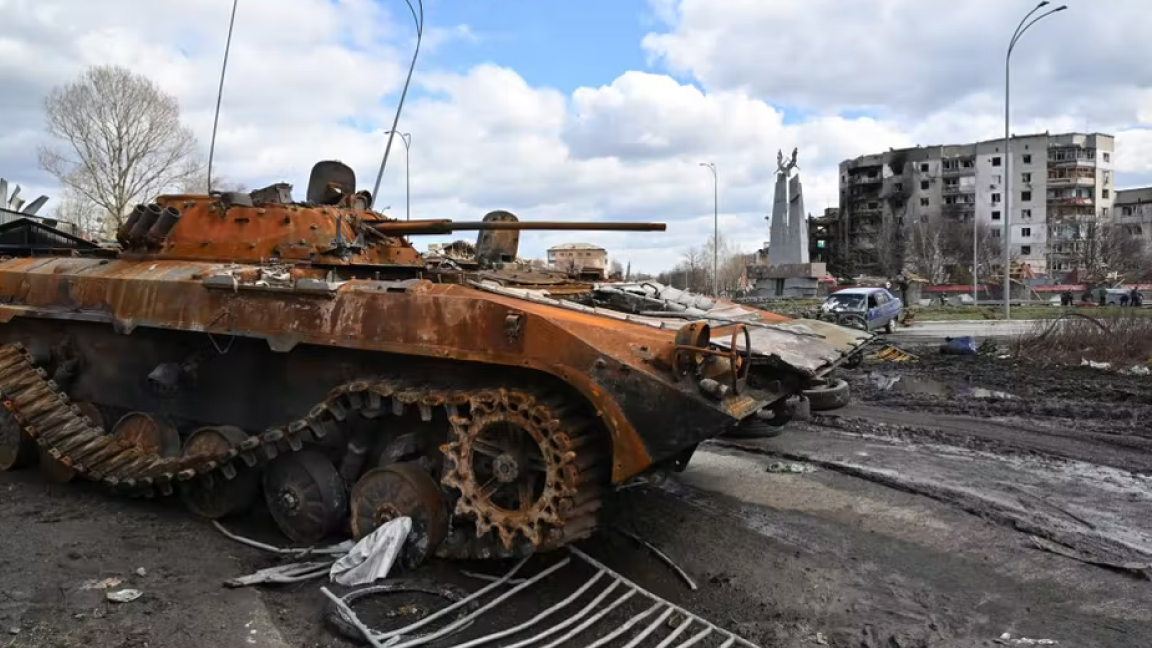 دبابة روسية مدمرة في وسط بلدة بوروديانكا ، بالقرب من كييف ، بالقرب من مبنى محترق، 4 أبريل 2022