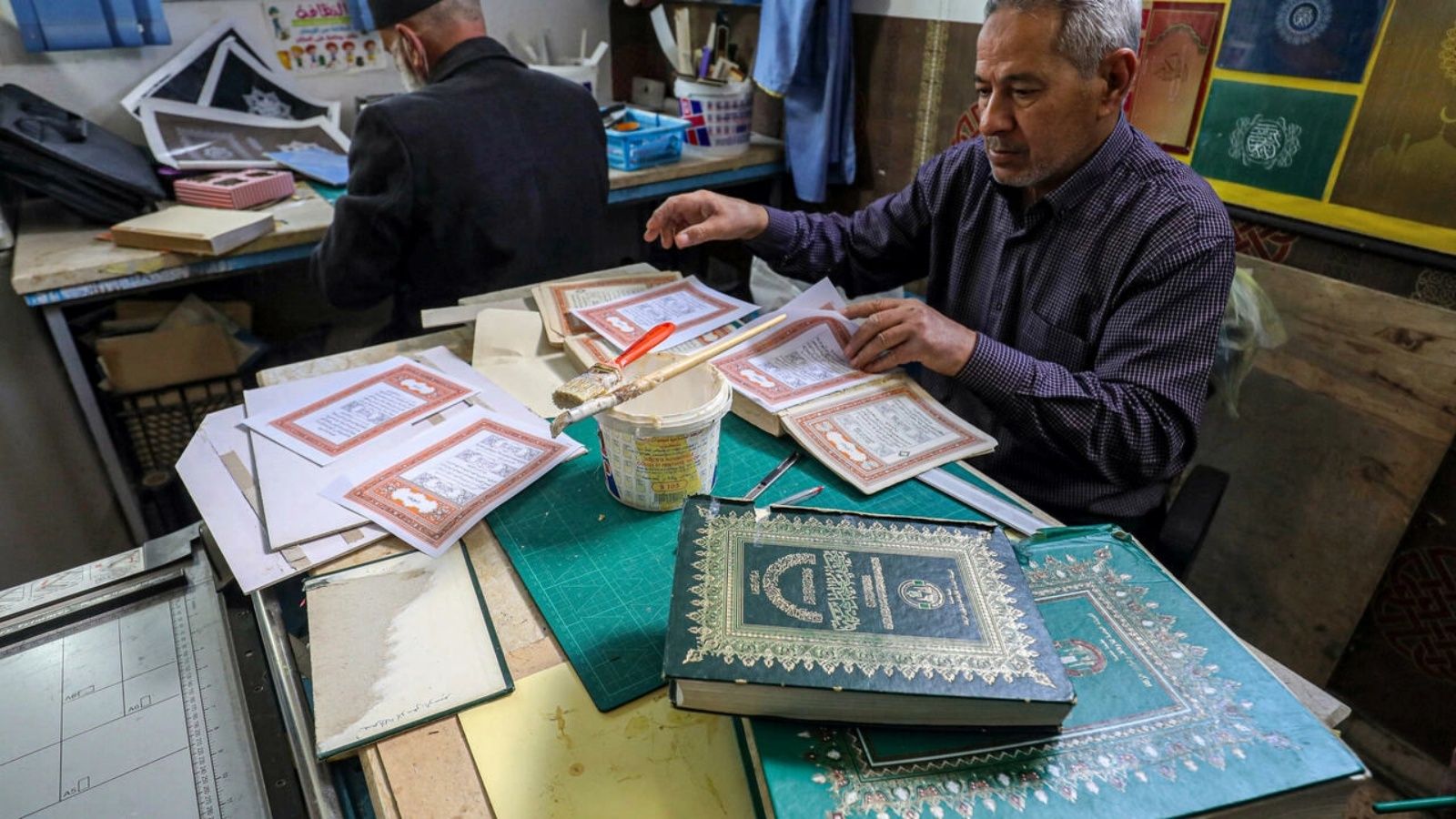 رجل يعمل على تأهيل مصحف قديم في إحدى الورش المخصصة للترميم في ليبيا