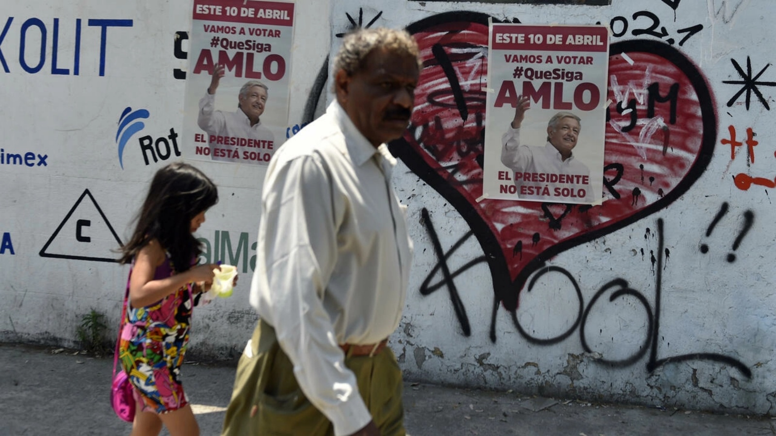 أشخاص يمشون بجوار ملصقات تروج لاستفتاء سحب الثقة من الرئاسة في مكسيكو سيتي