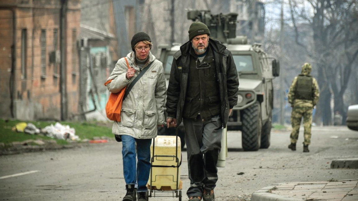 شخصان يمشيان في وسط مدينة ماريوبول بأوكرانيا في 12 أبريل 2022