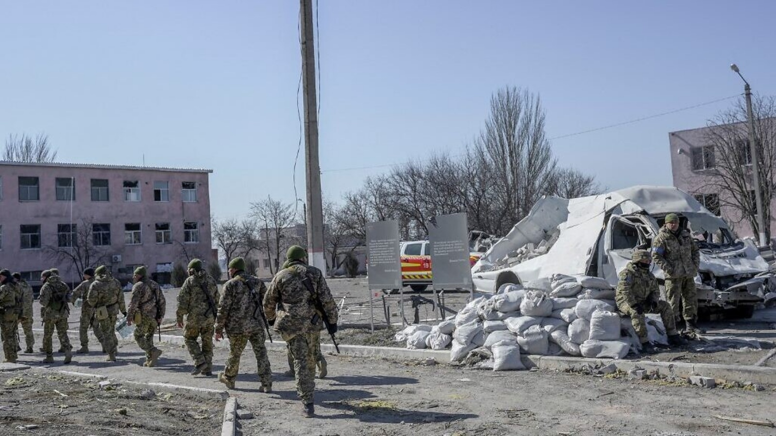 جنود أوكرانيون يسيرون بجوار مدرسة عسكرية أصيبت بصواريخ روسية في جنوب أوكرانيا، في 19 مارس 2022
