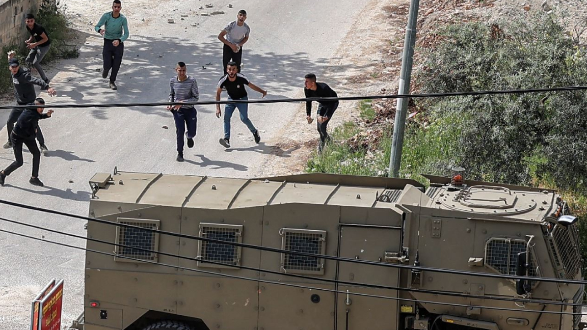فلسطينيون يرشقون سيارة عسكرية إسرائيلية بالحجارة خلال مواجهات في مخيم جنين للاجئين الفلسطينيين في الضفة في 9 أبريل 2022