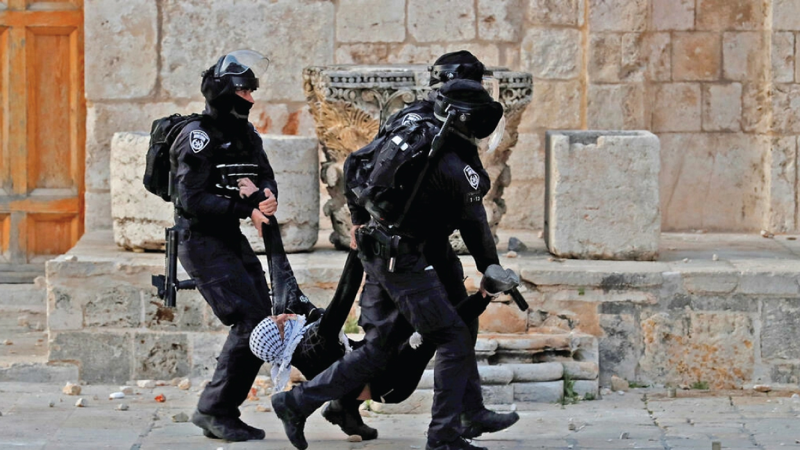عناصر من الشرطة الاسرائيلية يحملون متظاهرًا فلسطينيًا جريحًا أمام المسجد الأقصى في القدس في 22 أبريل 2022