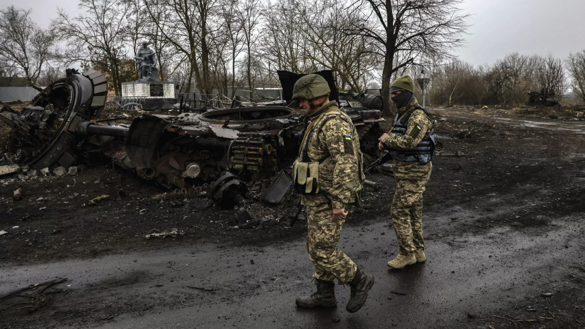 جنديان أوكرانيان أمام دبابة روسية مدمرة في إحدى الجبهات في كييف