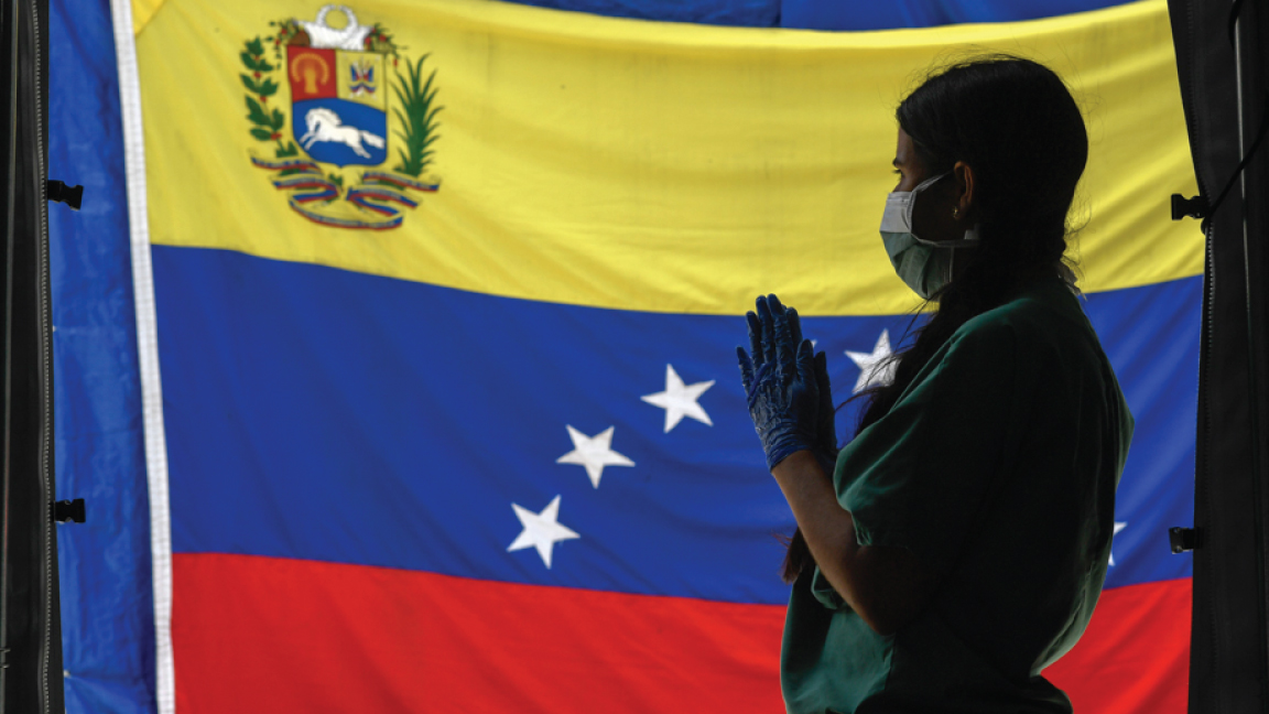 طبيب يقف أمام علم فنزيلا المعلق في أحد مستشفيات كراكاس