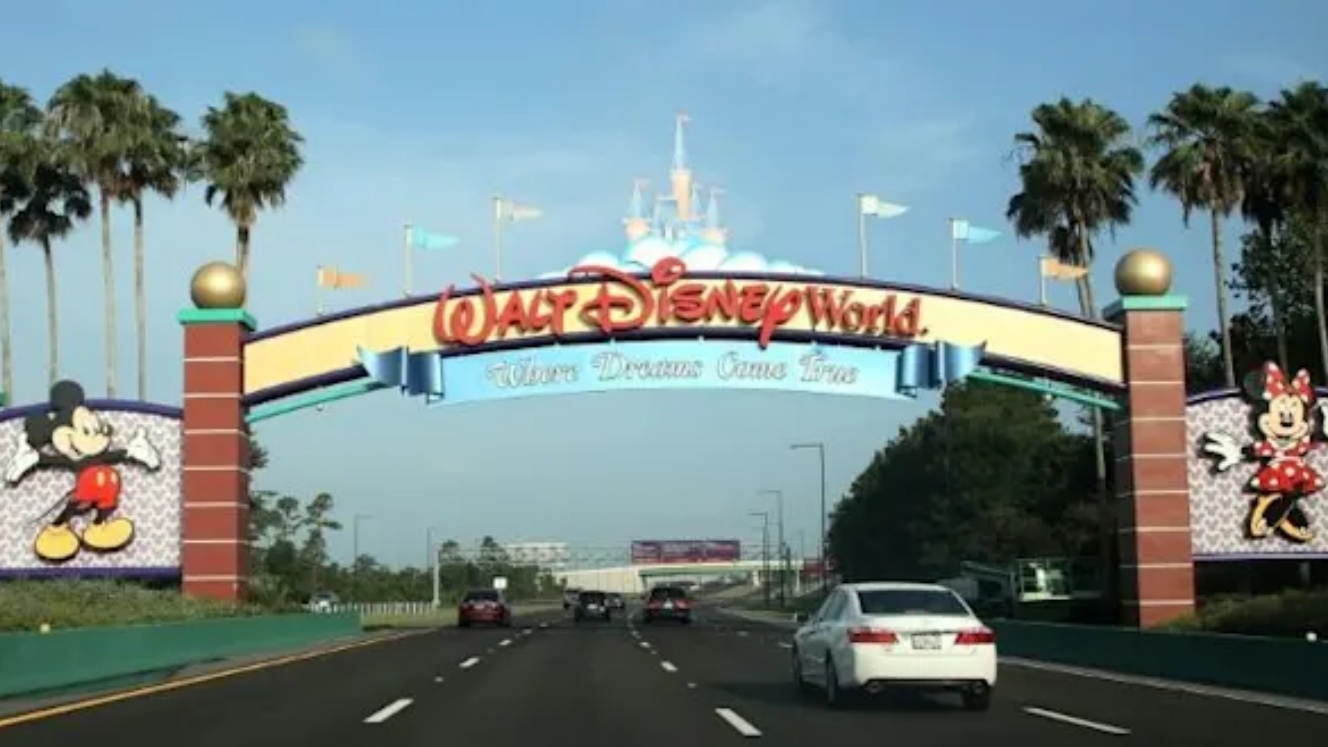 الزوار يمرون أمام لافتة ترحب بهم في عالم والت ديزني في أورلاندو بولاية فلوريدا في يوليو 2020