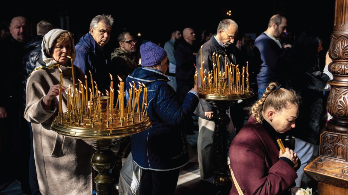مؤمنون يضيئون شموعا خلال حضورهم قداس عيد الفصح الأرثوذكسي في كاتدرائية القديس فولوديمير في كييف في 24 أبريل 2022