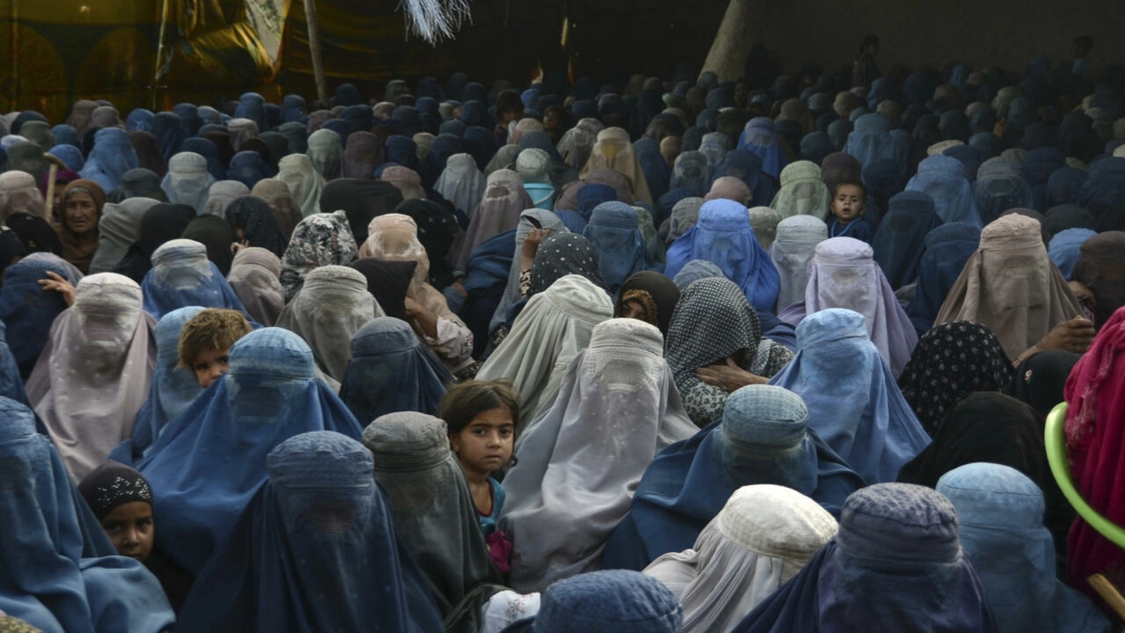 نساء وأطفالهن ينتظرن تلقي مساعدات غذائية في قندهار بتاريخ 27 أبريل 2022