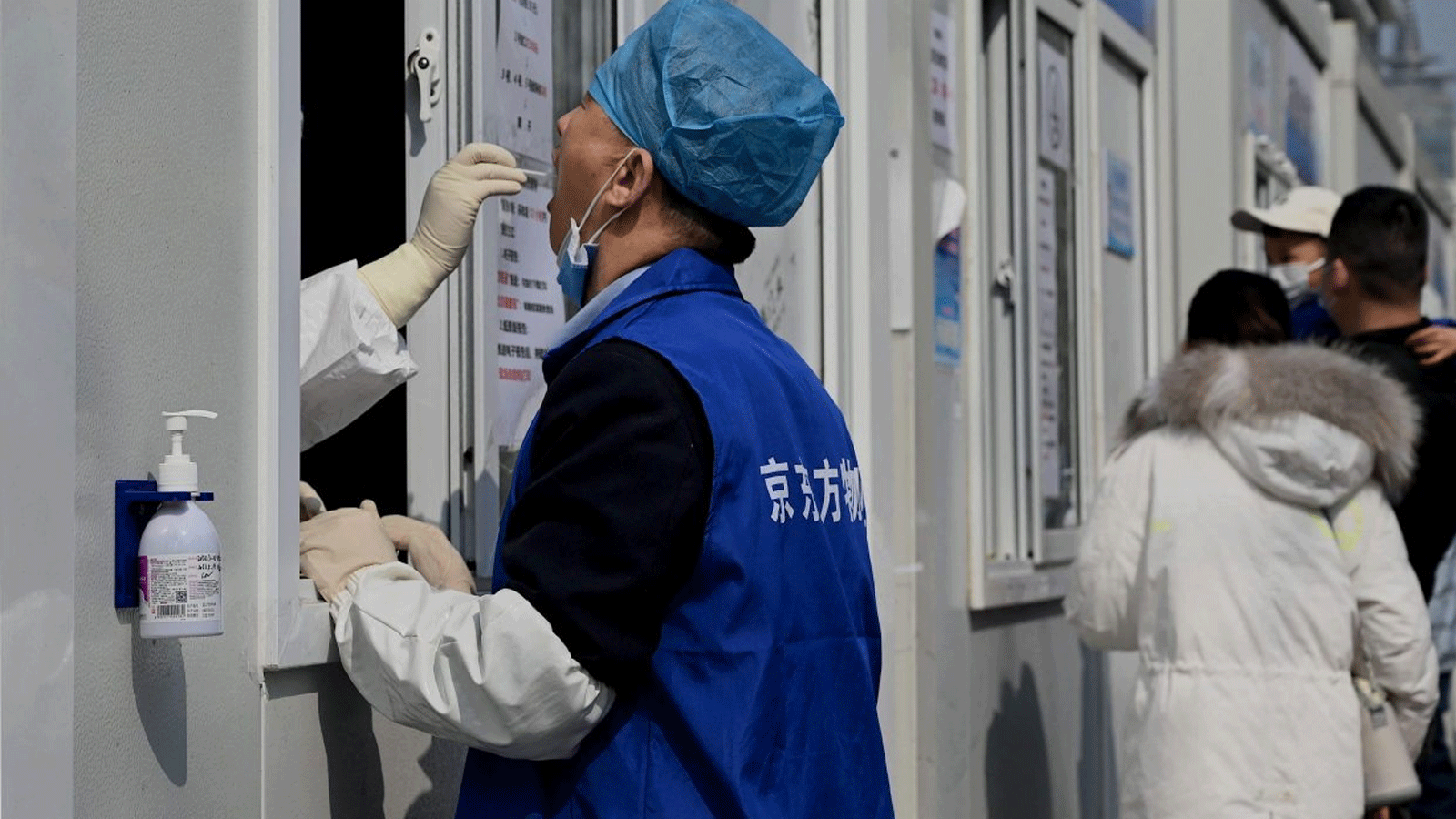  عاملٌ صحي يحصل على مسحة من امرأة لفحص فيروس كورونا Covid-19 في موقع جمع المسحات في بكين